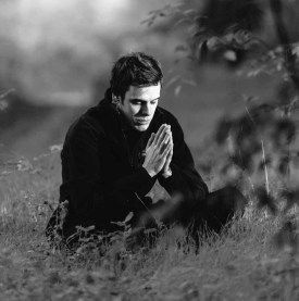 grayscale photography of man sitting on grass field